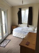 Bedroom 2 with a single bed, bedside cabinet, chest of drawers and a wardrobe. This room leads out to the back garden. 