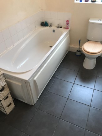 One of the upstairs bathrooms containing a bath (no shower head) a toilet and a sink.